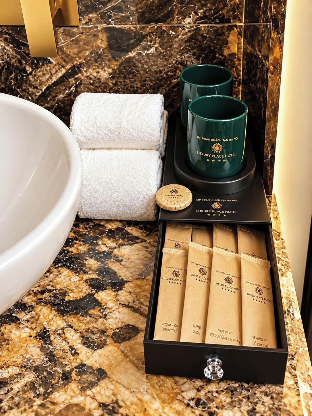 A bathroom vanity with a white sink, a towel, a green candle, and a box of toiletries.