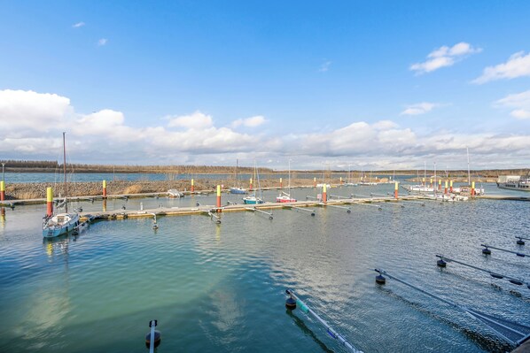 A marina with boats docked, calm water, and a clear sky.