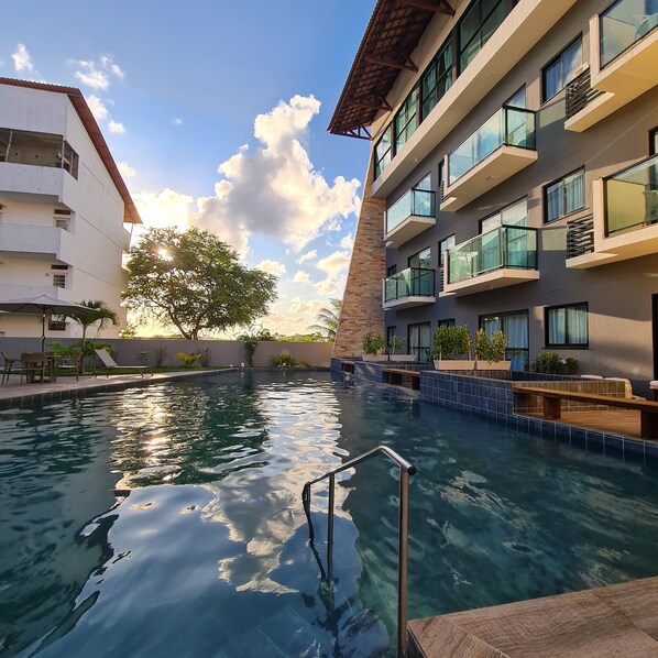 Una piscina con una escalera metálica, rodeada de edificios con balcones y terrazas.