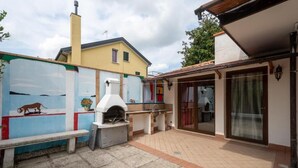 Un patio con horno de pizza, banco y un mural en la pared.