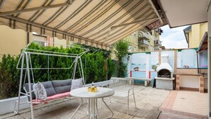 Un patio al aire libre con un columpio, una mesa redonda y una zona de barbacoa.
