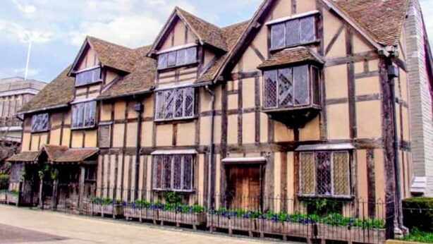 Una hilera de casas tradicionales con entramado de madera y techos empinados, con numerosas ventanas.