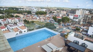 A rooftop pool with a clear view of the cityscape, including residential buildings and a construction crane in the distance. - Charming 1BR Suite | Rooftop Pool | Scenic City Views (Accra)