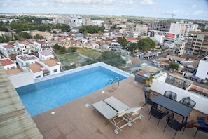 A rooftop pool with a clear view of the cityscape, including residential buildings and a construction crane in the distance. - Charming 1BR Suite | Rooftop Pool | Scenic City Views (Accra)