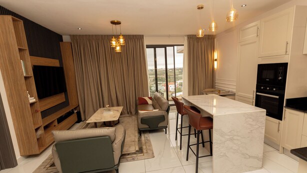 A modern living space with a kitchen, dining area, and seating. - Charming 1BR Suite | Rooftop Pool | Scenic City Views (Accra)