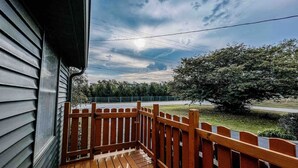 A wooden deck with a railing, overlooking a grassy area and a road. - 3 bd/ 10 min to dwtwn/Washer-Dryer (Indianapolis)