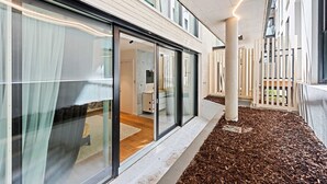 A modern building with large glass windows, a clean white facade, and a wooden deck area. - The Industrialist – Design Suite in Central Vienna (Vienna)