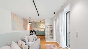 Un salon moderne avec un canapé, un tapis à motifs et une cuisine en arrière-plan.