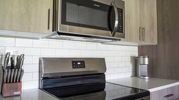 A kitchen with stainless steel appliances, including a microwave and oven, and a knife block.
