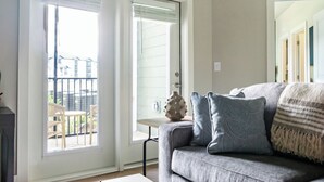 Een woonkamer met een grijze bank, gekleurde kussens en een bijzettafeltje met een vaas.