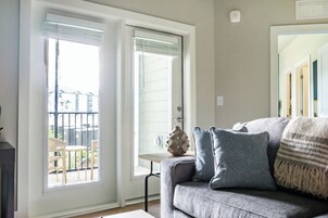 A living room with a grey sofa, patterned cushions, and a small table with a vase.
