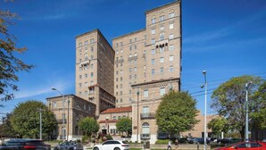 Un edificio de varios pisos con estilo arquitectónico clásico, que presenta una entrada central con un amplio arco y un asta de banderola.
