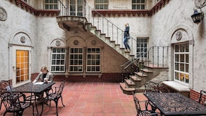 Un patio con una escalera, una mesa con sillas y una persona sentada a la mesa.