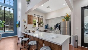 Una cocina moderna con una isla grande, taburetes de bar y vistas al exterior.