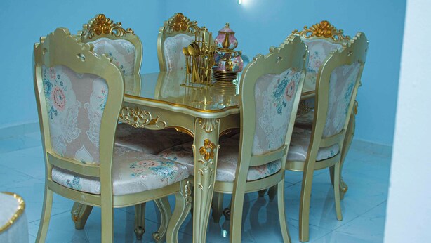 Une table à manger avec des chaises élégantes, un plateau en verre et un centre de table décoratif.