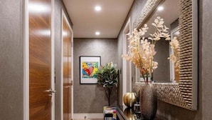 A hallway with wooden flooring, a console table with a vase and a mirror, and a framed artwork on the wall. - Luxury Apartment Near Notting Hill (London)