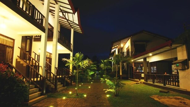 A pathway leading to a building with a staircase and a balcony.
