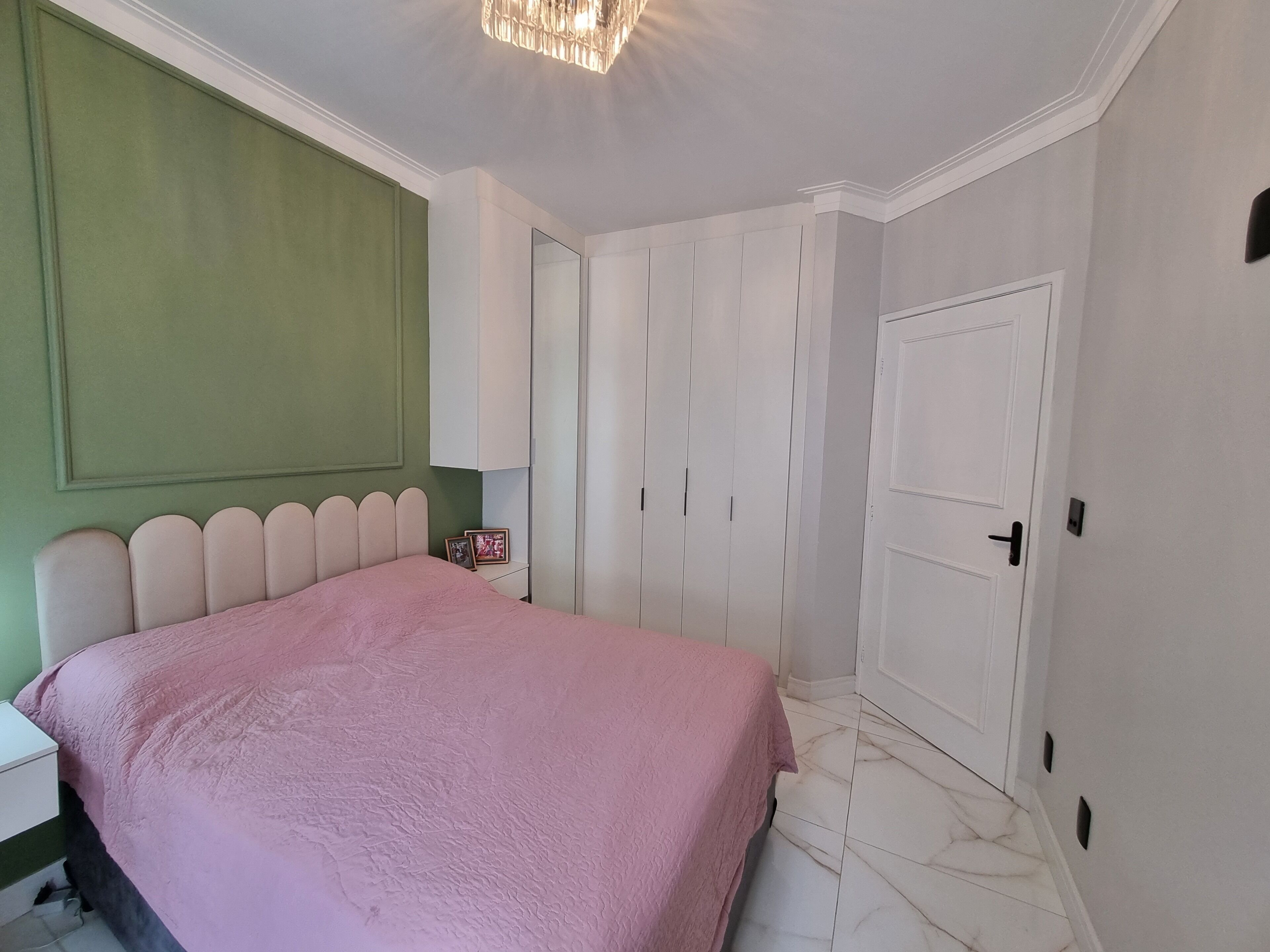 Een slaapkamer met een bed, een kledingkast en een deur.