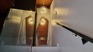 A modern staircase with a glass railing and a chandelier.