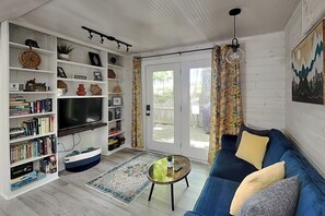 A living room with a TV, bookshelves, a sofa, a coffee table, and a patterned rug.