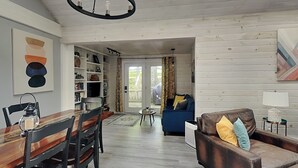 Amplia sala de estar con una mesa de comedor de madera, un sofá azul y una estantería.