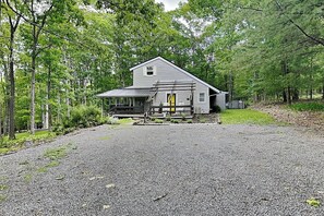 A single-story house with a porch, surrounded by trees.
