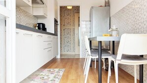 A compact kitchen with white cabinets, a dining table with chairs, and a patterned backsplash.