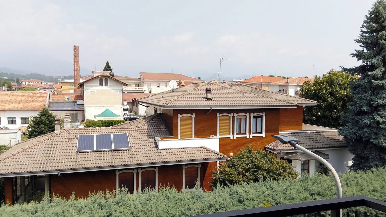 Zona residencial con casas, algunas con paneles solares, y una chimenea visible al fondo.