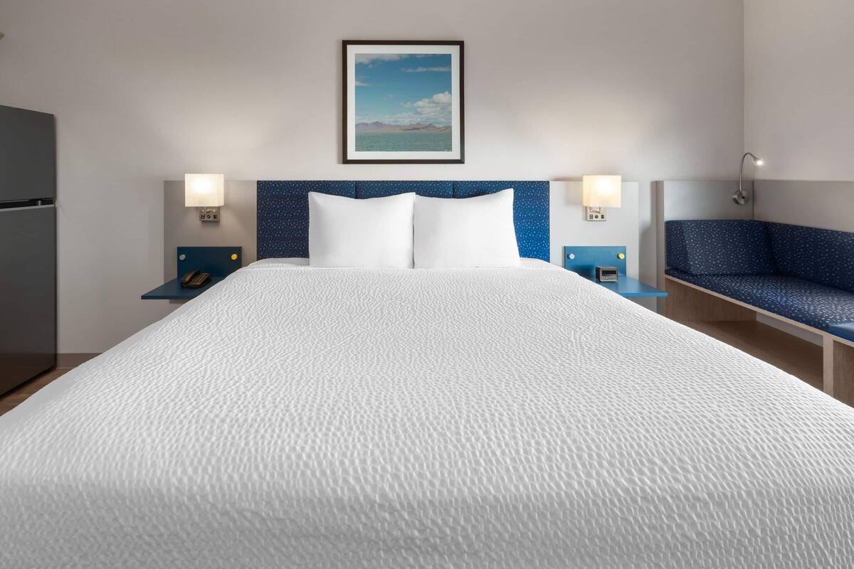 A hotel room with a large bed, two bedside tables with lamps, a small desk, and a chair.
