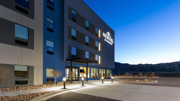 Un moderno edificio de hotel con varios pisos, ventanas amplias y un área de entrada bien iluminada.