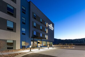 A modern hotel building with multiple floors, large windows, and a well-lit entrance area. - Microtel Inn & Suites By Wyndham Tooele (Tooele)