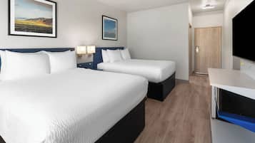 Une chambre d’hôtel avec deux lits, une télévision et une porte donnant sur une autre pièce.