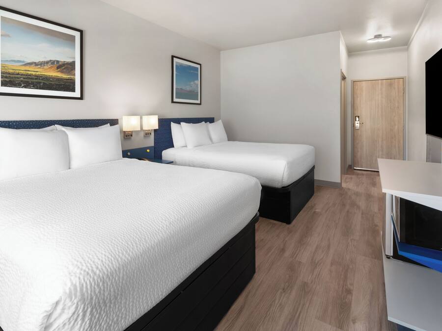 Une chambre d’hôtel avec deux lits, une télévision et une porte donnant sur une autre pièce.