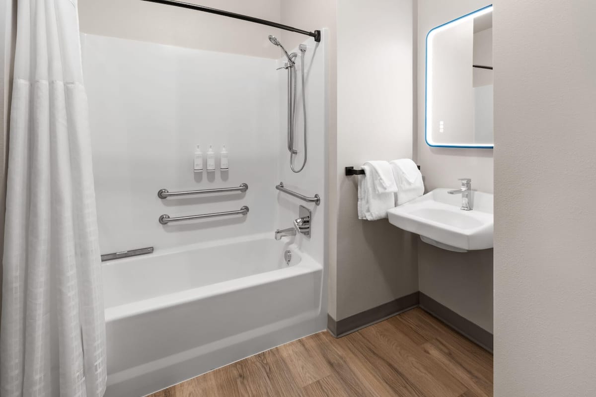 A modern bathroom with a bathtub, shower, and sink.