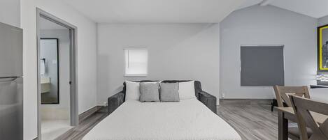 A modern bedroom with a bed, a desk, and a chair.