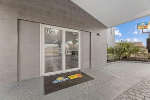 A modern hotel entrance with a glass door marked "1121," a Day Inn sign, and a Super 8 sign. - Super 8 by Wyndham Texas City/Galveston Area (Texas City)