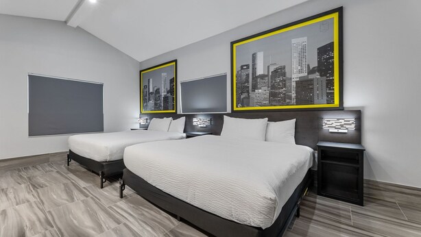 A modern hotel room with a large bed, two bedside tables, and three framed cityscape pictures on the wall. - Super 8 by Wyndham Texas City/Galveston Area (Texas City)