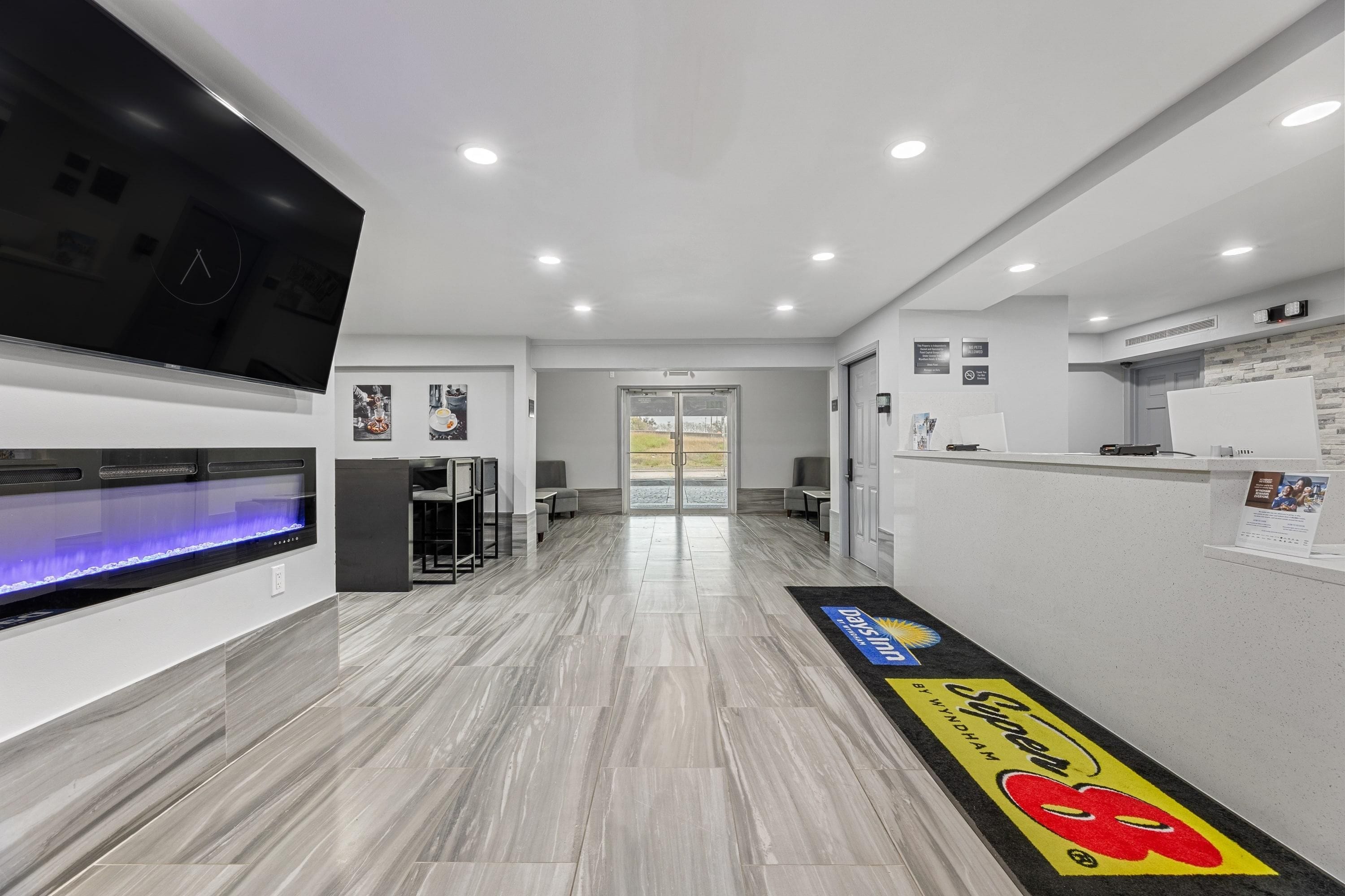 Un moderno vestíbulo de hotel con una recepción, zona de estar y un televisor de pantalla plana grande montado en la pared.