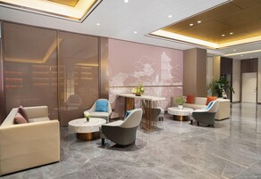 Un vestíbulo moderno con zonas de estar, una mesa central y una pared decorativa con el contorno de un edificio.