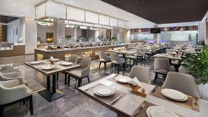 A modern restaurant with a central bar area, multiple dining tables, and a clean, contemporary design.