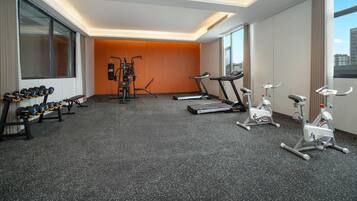 Un gimnasio moderno de hotel con cintas de correr, bicicletas estáticas y mancuernas.