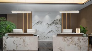 A reception area with marble counters, two sinks, and a backdrop of a marble mountain design.