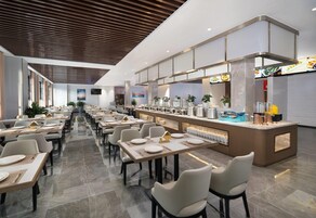 Um restaurante moderno com um balcão extenso, diversas mesas e diferentes opções de assento.