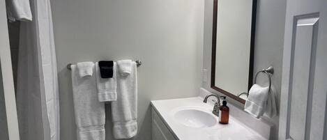 A bathroom with a white sink, a mirror, and a towel rack with multiple towels.