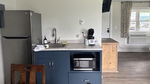 A compact kitchen with a refrigerator, microwave, sink, and wooden cabinet. - Juniper Motel-King Suite-RM12*Efficiency Kitchen*Lakefront*ATV Access (Greenville)