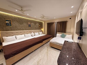 A hotel room with a large bed, a smaller bed, a TV, and a minibar.