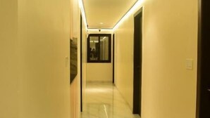 A long, well-lit hallway with a shiny floor, leading to a door at the end.
