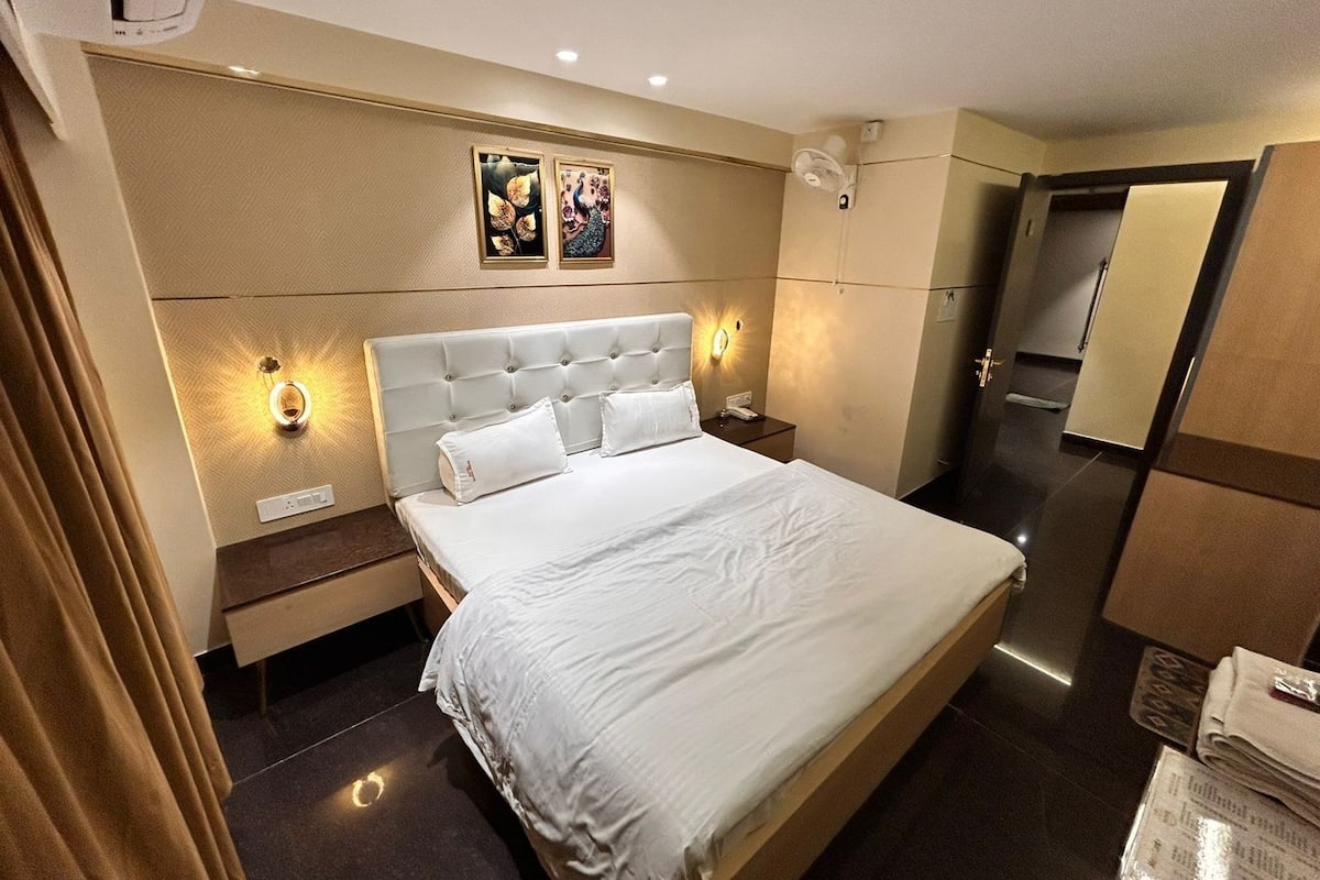 Ein modernes Hotelzimmer mit einem großen Bett, zwei Nachttischen, einer Ablagefläche und einer Wandleuchte sowie einem Spiegel.