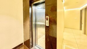 An elevator in a hallway with a control panel on the wall.