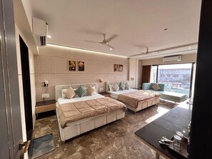 A modern hotel room with two beds, a dining table, and a large window offering a city view. - Hotel Mangal Shree (Ujjain)